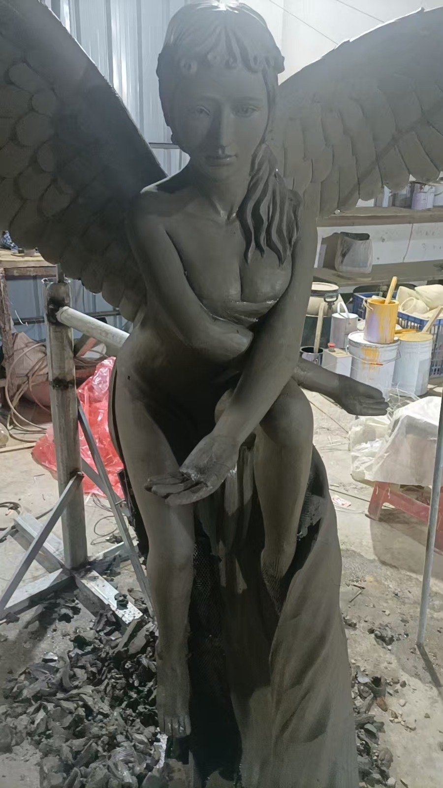 Close view of a fiberglass angel sculpture during workshop fabrication and surface preparation