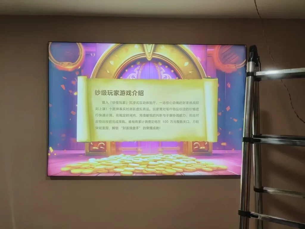 A wall-mounted screen displays the introduction to the “钞级玩家” interactive game; a ladder is visible beside it.